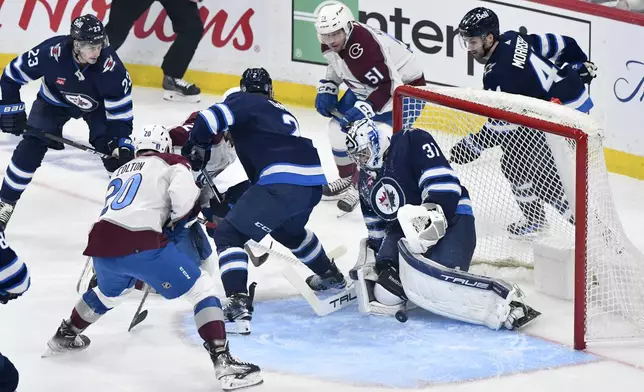 Winnipeg Jets goaltender Connor Hellebuyck (37) makes a save on Colorado Avalanche's Ross Colton (20) during the first period in Game 5 of an NHL hockey Stanley Cup first-round playoff series in Winnipeg, Manitoba, Tuesday April 30, 2024. (Fred Greenslade/The Canadian Press via AP)