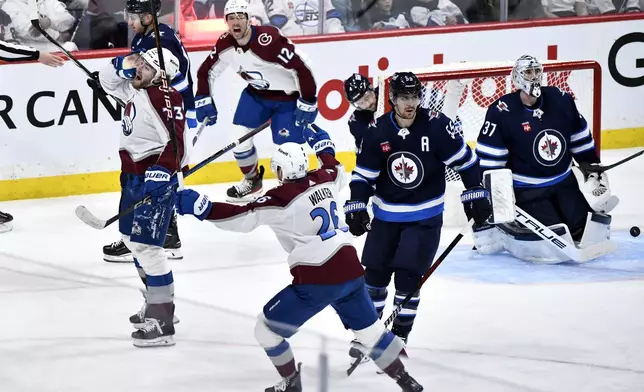 Colorado Avalanche's Yakov Trenin (73) celebrates his goal with teammates on Winnipeg Jets goaltender Connor Hellebuyck (37) during the second period in Game 5 of an NHL hockey Stanley Cup first-round playoff series in Winnipeg, Manitoba, Tuesday, April 30, 2024. (Fred Greenslade/The Canadian Press via AP)