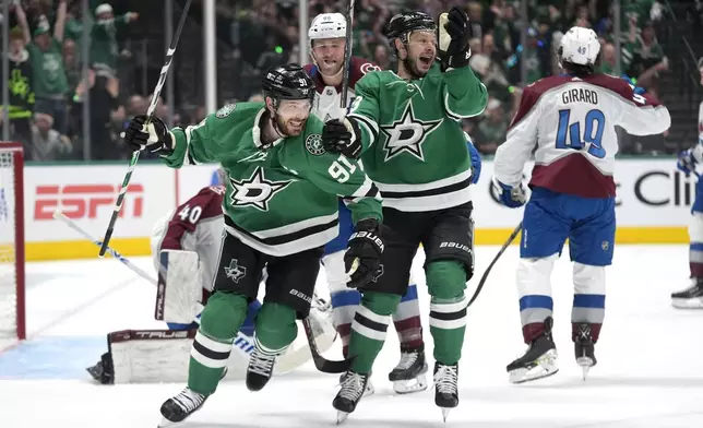 Dallas Stars' Tyler Seguin (91) and Evgenii Dadonov, center right, celebrate in front of Colorado Avalanche defenseman Samuel Girard (49) after the Stars' Ryan Suter scored in the first period in Game 2 of an NHL hockey Stanley Cup second-round playoff series in Dallas, Tuesday, May 7, 2024. (AP Photo/LM Otero)