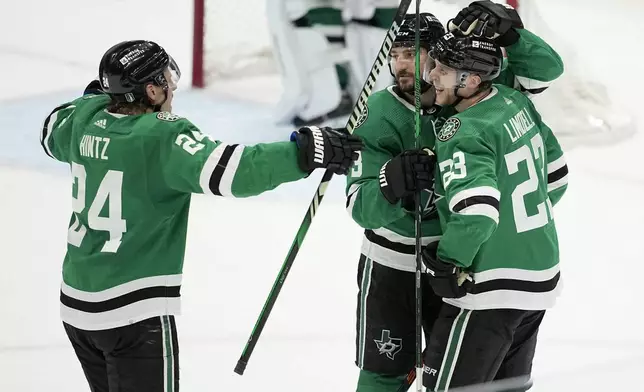 Dallas Stars' Roope Hintz (24), Chris Tanev (3) and Esa Lindell (23) celebrate Lindell's empty-net goal against the Colorado Avalanche late in the third period in Game 2 of an NHL hockey Stanley Cup second-round playoff series in Dallas, Thursday, May 9, 2024. (AP Photo/Tony Gutierrez)