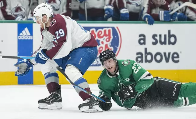 Dallas Stars defenseman Esa Lindell (23) falls on the ice while challenging Colorado Avalanche center Nathan MacKinnon (29) for the puck during the second period in Game 5 of an NHL hockey Stanley Cup second-round playoff series, Wednesday, May 15, 2024, in Dallas. (AP Photo/Tony Gutierrez)