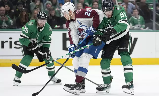 Colorado Avalanche center Nathan MacKinnon (29) attempts to control the puck under pressure from Dallas Stars center Matt Duchene (95) and center Tyler Seguin (91) during the first period in Game 2 of an NHL hockey Stanley Cup second-round playoff series in Dallas, Thursday, May 9, 2024. (AP Photo/Tony Gutierrez)