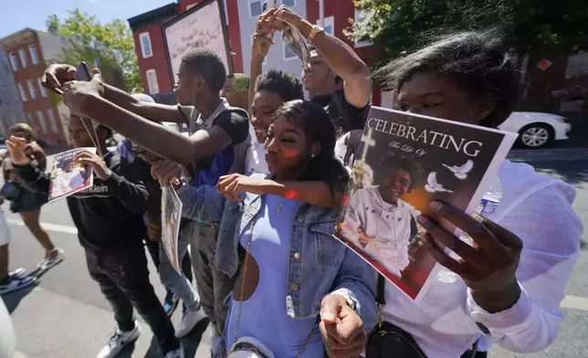A photograph of Antonio Lee is seen on a program as mourners gather for photographs following a funeral service for Lee, Thursday, Aug. 31, 2023, in Baltimore. Lee, 19, a squeegee worker was killed during a shooting as he panhandled in a Baltimore street corner. (AP Photo/Julio Cortez)