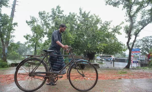 A Bangladeshi man pushes his bicycle during a rain after Cyclone Remal lashed Bangladesh’s southern coast in Shyamnagar, Satkhira District, Bangladesh, Monday, May 27, 2024. (AP Photo/Abdul Goni)