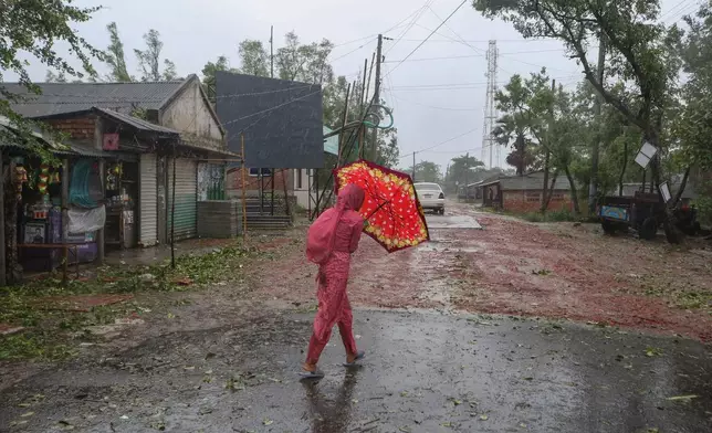 A Bangladeshi woman walks holding an umbrella during a rain after Cyclone Remal lashed Bangladesh’s southern coast in Shyamnagar, Satkhira District, Bangladesh, Monday, May 27, 2024. (AP Photo/Abdul Goni)