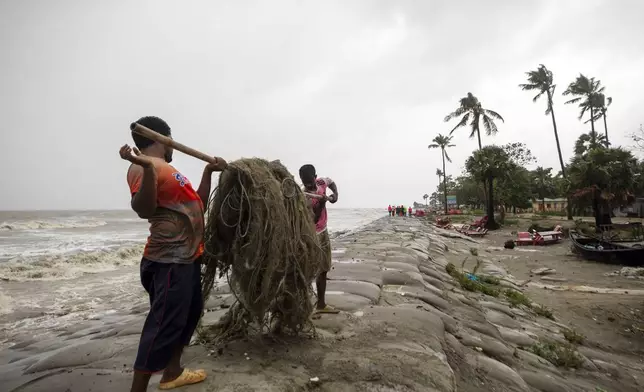 Men move fishing nets as water flows on to the Kuakata beach on the coast of Bay of Bengal caused by the advancing Cyclone Remal in Barisal, Bangladesh, Sunday, May 26, 2024. (AP Photo/Abdul Goni)