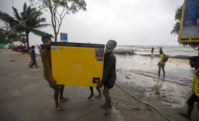 Men salvage a refrigerator as water flows on to the Kuakata beach on the coast of Bay of Bengal caused by the advancing Cyclone Remal in Barisal, Bangladesh, Sunday, May 26, 2024. (AP Photo/Abdul Goni)