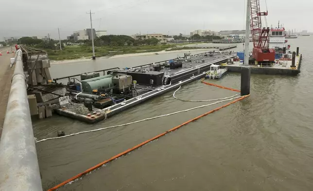 Spill booms surround a barge at the Pelican Island bridge in Galveston, Texas, Wednesday, May 16, 2024. The barge collided with the bridge Tuesday which caused a partial collapse of the bridge and spilled vacuum gas oil the barge was carrying into Galveston Bay. (Jennifer Reynolds/The Galveston County Daily News via AP)
