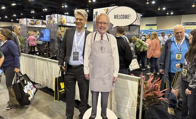 Berkshire Hathaway shareholders pose with a cutout poster of CEO Warren Buffett Friday, May 3, 2024, in Omaha, Neb., inside the exhibit hall in Omaha where Berkshire companies sell their products. Buffett will spend hours answering questions at the meeting Saturday. (AP Photo/Josh Funk)