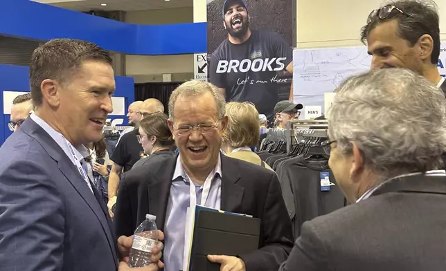 Berkshire Hathaway investment manager Ted Weschler, center, talks with Brooks Running CEO Dan Sheridan, Friday, May 3, 2024, in Omaha, Neb., one day ahead of the annual shareholders meeting. (AP Photo/Josh Funk)