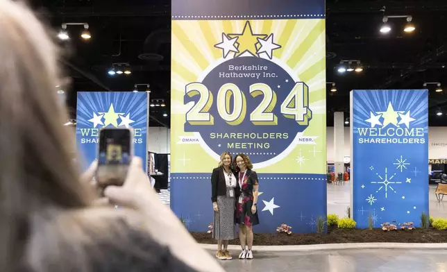 From left, D'Ann Rhoten takes a photo of Brittany Thornton and Melissa Shapiro in the exhibit hall of the Berkshire Hathaway annual meeting on Saturday, May 4, 2024, in Omaha, Neb. (AP Photo/Rebecca S. Gratz)