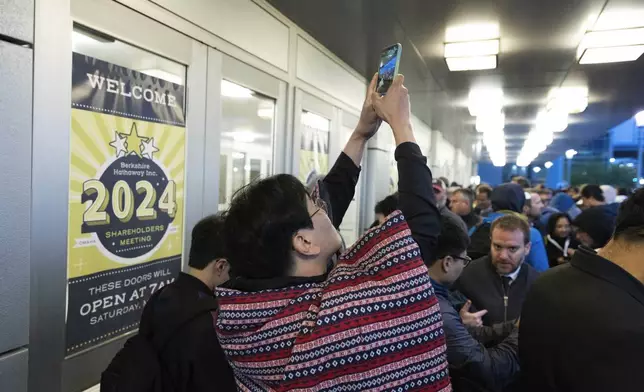 Daegwon Kim of South Korea, who arrived in line at 3:30 a.m., takes photos of the crowd behind him outside the Berkshire Hathaway annual meeting on Saturday, May 4, 2024, in Omaha, Neb. (AP Photo/Rebecca S. Gratz)