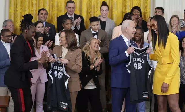 A'ja Wilson, right, Chelsea Gray, left, of the WNBA's Las Vegas Aces, present jerseys to President Joe Biden, center right, and Vice President Kamala Harris, center left, during an event to celebrate the 2023 WNBA championship team, in the East Room of the White House, Thursday, May 9, 2024, in Washington. (AP Photo/Evan Vucci)