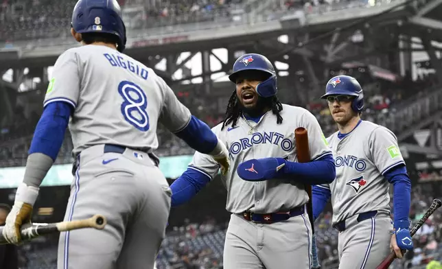 Toronto Blue Jays' Vladimir Guerrero Jr., center, is greeted by Cavan Biggio (8) and Danny Jansen, right, after scoring on a fielder's choice hit into by Daniel Vogelbach during the first inning of a baseball game against the Washington Nationals, Saturday, May 4, 2024, in Washington. (AP Photo/Nick Wass)