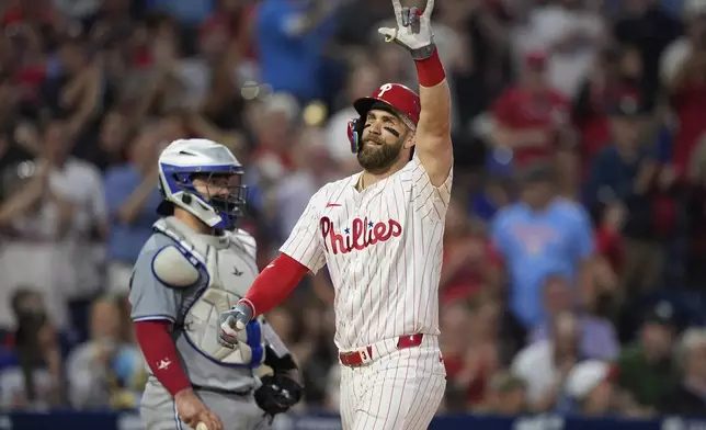 Philadelphia Phillies' Bryce Harper, right, reacts past Toronto Blue Jays catcher Alejandro Kirk after hitting a grand slam during the fourth inning of a baseball game, Tuesday, May 7, 2024, in Philadelphia. (AP Photo/Matt Slocum)