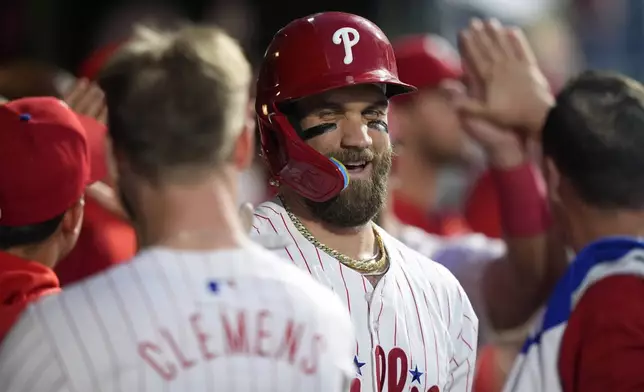 Philadelphia Phillies' Bryce Harper, center, celebrates with Kody Clemens and teammates after hitting a grand slam against Toronto Blue Jays pitcher Jose Berrios during the fourth inning of a baseball game, Tuesday, May 7, 2024, in Philadelphia. (AP Photo/Matt Slocum)
