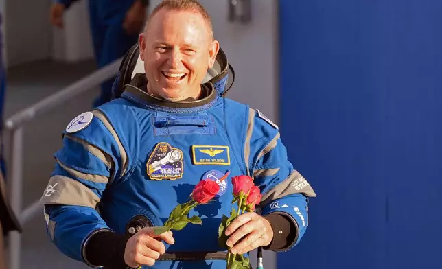 NASA astronaut Butch Wilmore carries roses to hand out to relatives as he leaves the Operations and Checkout building before heading to Space Launch Complex 41 to board the Boeing's Starliner capsule atop an Atlas V rocket for a mission to the International Space Station at the Cape Canaveral Space Force Station Monday, May 6, 2024, in Cape Canaveral, Fla. (AP Photo/John Raoux)
