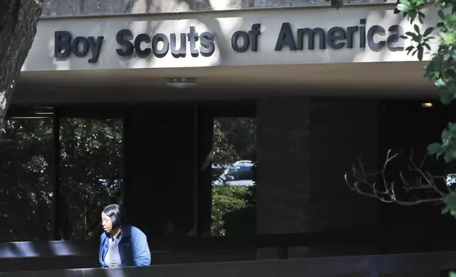 FILE - A woman walks out of the Boy Scouts of America national headquarters building in Irving, Texas, Nov. 1, 2019. The U.S. organization, which now welcomes girls into the program and allows them to work toward the coveted Eagle Scout rank, announced Tuesday, May 7, 2024, that it will change its name to Scouting America as it focuses on inclusion. (AP Photo/LM Otero, File)