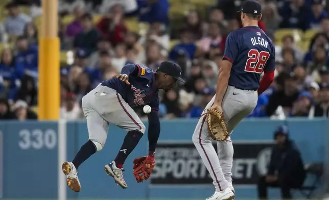 Atlanta Braves second baseman Ozzie Albies, left, does not catch a fly ball hit by Los Angeles Dodgers' Mookie Betts during the seventh inning of a baseball game in Los Angeles, Saturday, May 4, 2024. Atlanta Braves first baseman Matt Olson is at right. (AP Photo/Ashley Landis)