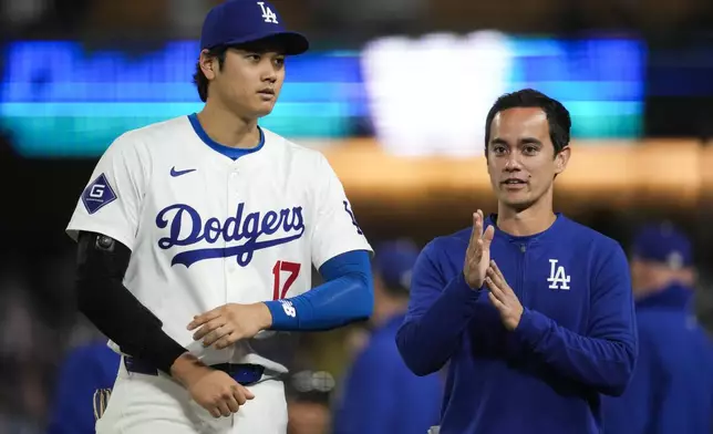 Los Angeles Dodgers designated hitter Shohei Ohtani (17) walks with his interpreter, Will Ireton, after a baseball game against the Atlanta Braves in Los Angeles, Saturday, May 4, 2024. (AP Photo/Ashley Landis)