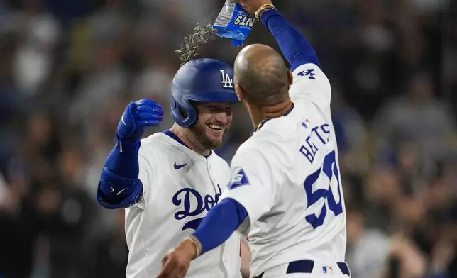 Los Angeles Dodgers' Max Muncy celebrates with Mookie Betts (50) after hitting a home run during the eighth inning of a baseball game against the Atlanta Braves in Los Angeles, Saturday, May 4, 2024. (AP Photo/Ashley Landis)