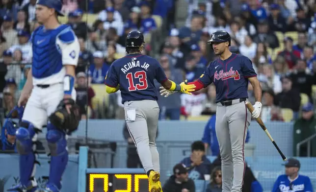 Atlanta Braves' Ronald Acuña Jr. (13) is greeted by Matt Olson, right, after scoring off of a single hit by Austin Riley during the fourth inning of a baseball game against the Los Angeles Dodgers in Los Angeles, Saturday, May 4, 2024. (AP Photo/Ashley Landis)