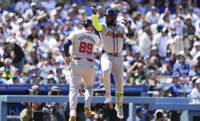 Atlanta Braves designated hitter Marcell Ozuna, right, celebrates with third base coach Matt Tuiasosopo (89) after hitting a home run during the seventh inning of a baseball game against the Los Angeles Dodgers in Los Angeles, Sunday, May 5, 2024. (AP Photo/Ashley Landis)