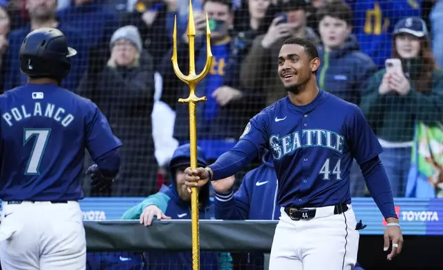 Seattle Mariners' Julio Rodríguez (44) hands a trident to Jorge Polanco (7) to celebrate Polanco's two-run home run against the Atlanta Braves during the third inning of a baseball game Tuesday, April 30, 2024, in Seattle. (AP Photo/Lindsey Wasson)