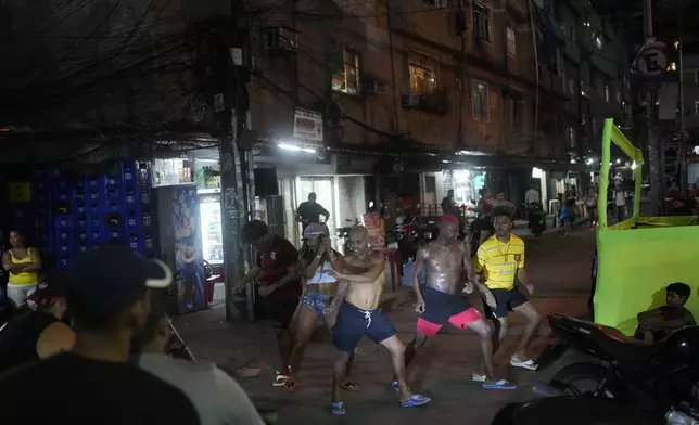 FILE - Illuminated by a motorcycle headlight, youth perform a street dance known as passinho in the Rocinha favela of Rio de Janeiro, Brazil, April 11, 2024. The passinho, or "little step", created in the 2000s by kids in Rio's favelas, was declared an "intangible cultural heritage" by state legislators, bringing recognition to a cultural expression born in the sprawling working-class neighborhoods. (AP Photo/Silvia Izquierdo, File)