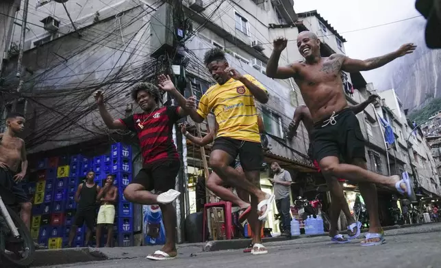 FILE - Youth perform a street dance style known as passinho for their social media accounts, in the Rocinha favela of Rio de Janeiro, Brazil, April 11, 2024. The passinho, or "little step", created in the 2000s by kids in Rio's favelas, was declared an "intangible cultural heritage" by state legislators, bringing recognition to a cultural expression born in the sprawling working-class neighborhoods. (AP Photo/Silvia Izquierdo, File)
