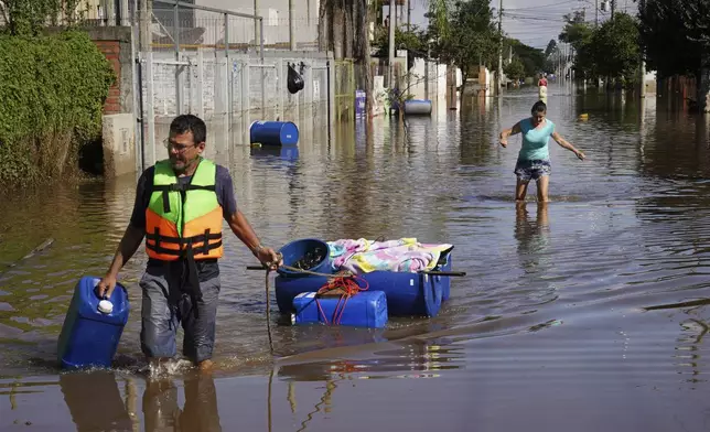 A resident pulls belongings he recovered from his flooded home after heavy rain in Canoas, Rio Grande do Sul state, Brazil, Thursday, May 9, 2024. (AP Photo/Carlos Macedo)