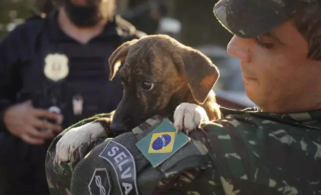 A Brazilian soldier carries a dog after rescuing it from a flooded area after heavy rain in Canoas, Rio Grande do Sul state, Brazil, Thursday, May 9, 2024. (AP Photo/Carlos Macedo)