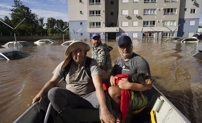 People rescue a dog named Maia from a flooded area after heavy rain in Canoas, Rio Grande do Sul state, Brazil, Thursday, May 9, 2024. (AP Photo/Carlos Macedo)