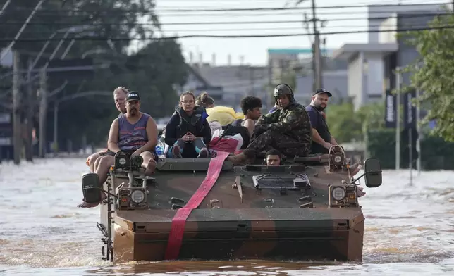 Residents are evacuated in a military vehicle from an area flooded by heavy rains, in Porto Alegre, Brazil, Tuesday, May 7, 2024. (AP Photo/Andre Penner)