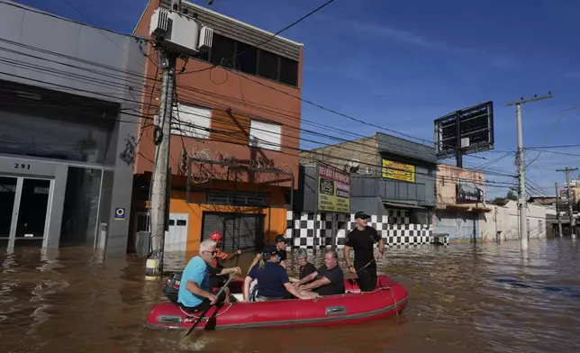 Volunteers evacuate residents from an area flooded by heavy rains, in Porto Alegre, Brazil, Tuesday, May 7, 2024. (AP Photo/Andre Penner)