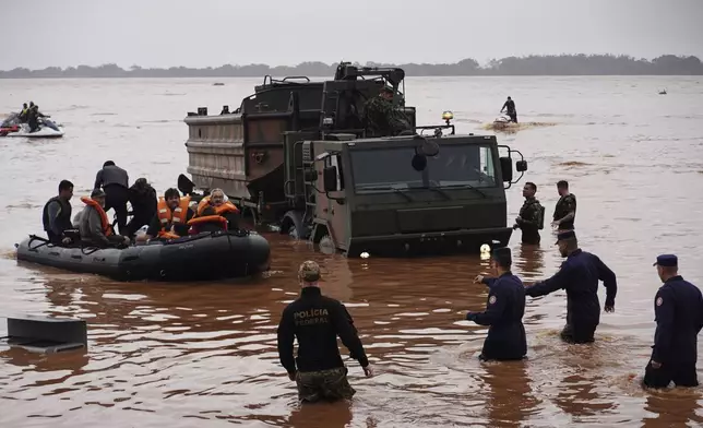 Brazilian soldiers and federal police evacuate residents from an area flooded by heavy rains in Porto Alegre, Rio Grande do Sul state, Brazil, Saturday, May 4, 2024. (AP Photo/Carlos Macedo)