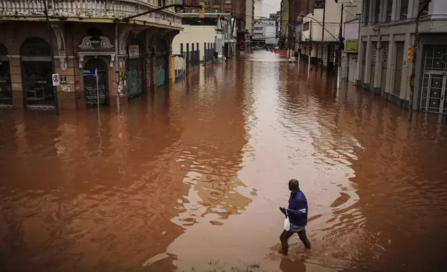 A man wades through an area flooded by heavy rains, in Porto Alegre, Rio Grande do Sul state, Brazil, Friday, May 3, 2024. (AP Photo/Carlos Macedo)