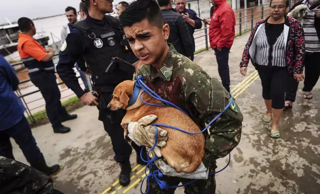 A soldier evacuates a dog from an area flooded by heavy rains, in Porto Alegre, Rio Grande do Sul state, Brazil, Friday, May 3, 2024. (AP Photo/Carlos Macedo)
