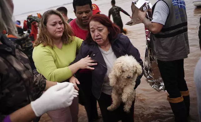 A woman and her pet are rescued from an area flooded by heavy rains in Porto Alegre, Rio Grande do Sul state, Brazil, Saturday, May 4, 2024. (AP Photo/Carlos Macedo)