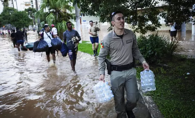 A military police carries water bottles for flood victims after heavy rains in Porto Alegre, Rio Grande do Sul state, Brazil, Monday, May 6, 2024. (AP Photo/Carlos Macedo)