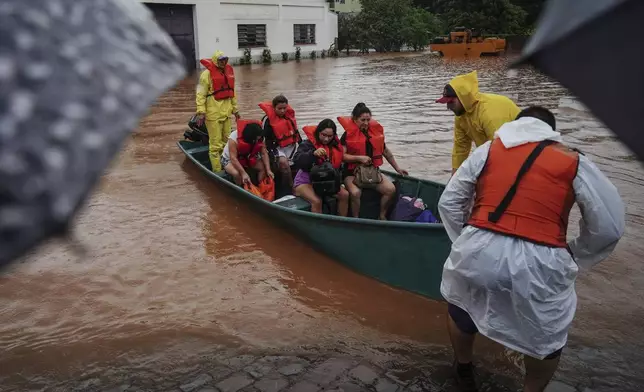 Firefighters evacuate people from a flooded area after heavy rain in Sao Sebastiao do Cai, Rio Grande do Sul state, Brazil, Thursday, May 2, 2024. (AP Photo/Carlos Macedo)