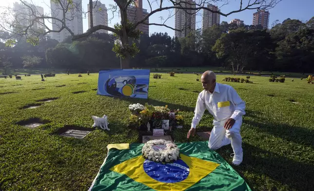 A fan kneels at the burial site of late Brazilian Formula One driver Ayrton Senna as fans gather to mark the 30th anniversary of his death, at Morumbi cemetery in Sao Paulo, Brazil, Wednesday, May 1, 2024. The three-time F1 world champion died in a crash at the Imola race track in San Marino. (AP Photo/Andre Penner)