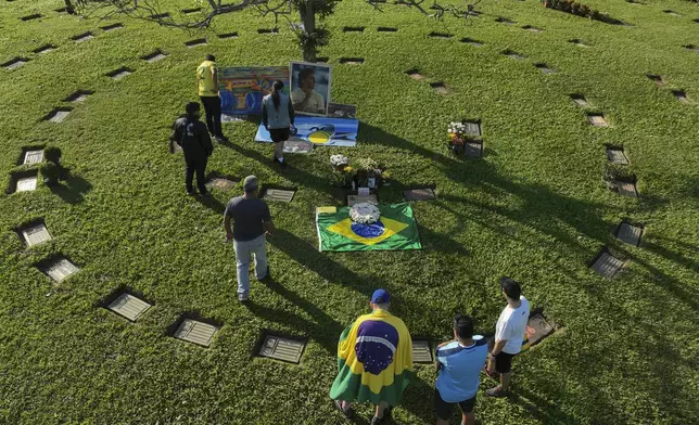 Fans gather at the burial site of late Brazilian Formula One driver Ayrton Senna to mark the 30th anniversary of his death, at Morumbi cemetery in Sao Paulo, Brazil, Wednesday, May 1, 2024. The three-time F1 world champion died in a crash at the Imola race track in San Marino. (AP Photo/Andre Penner)