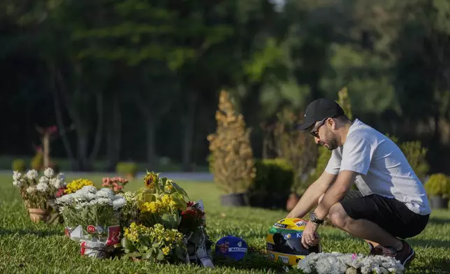 A fan visits the burial site of late Brazilian Formula One driver Ayrton Senna on the 30th anniversary of his death, at Morumbi cemetery in Sao Paulo, Brazil, Wednesday, May 1, 2024. The three-time F1 world champion died in a crash at the Imola race track in San Marino. (AP Photo/Andre Penner)