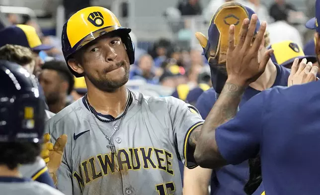 Milwaukee Brewers' Blake Perkins (16) is high-fived in the dugout after scoring on a single hit by William Contreras during the fourth inning of a baseball game against the Miami Marlins, Tuesday, May 21, 2024, in Miami. (AP Photo/Lynne Sladky)