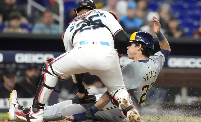 Milwaukee Brewers' Christian Yelich (22) is tagged out at the plate by Miami Marlins catcher Christian Bethancourt (25) during the third inning of a baseball game, Tuesday, May 21, 2024, in Miami. (AP Photo/Lynne Sladky)