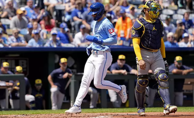 Kansas City Royals' Bobby Witt Jr., left, runs past Milwaukee Brewers catcher William Contreras to score on a sacrifice fly hit by Michael Massey during the first inning of a baseball game Wednesday, May 8, 2024, in Kansas City, Mo. (AP Photo/Charlie Riedel)
