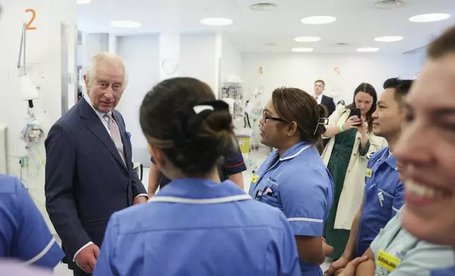 FILE - Britain's King Charles III meets with staff members during a visit to the University College Hospital Macmillan Cancer Centre in London, Britain, Tuesday,April 30, 2024. King Charles III’s decision to be open about his cancer diagnosis has helped the new monarch connect with the people of Britain and strengthened the monarchy in the year since his dazzling coronation at Westminster Abbey. (Suzanne Plunkett/Pool photo via AP, File)