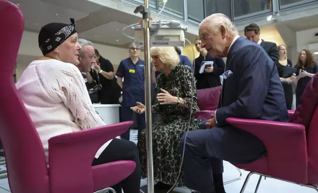 FILE - Britain's King Charles III and Queen Camilla meet with Lesley Woodbridge, patient receiving the second round of chemotherapy for sarcoma and her husband Roger Woodbridge during a visit to the University College Hospital Macmillan Cancer Centre in London, Tuesday April 30, 2024. King Charles III’s decision to be open about his cancer diagnosis has helped the new monarch connect with the people of Britain and strengthened the monarchy in the year since his dazzling coronation at Westminster Abbey. (Suzanne Plunkett, Pool Photo via AP, File)
