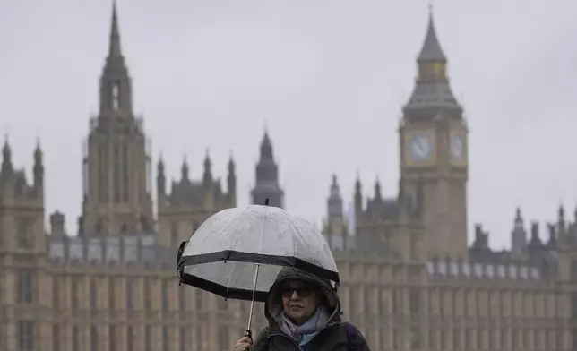 A woman holds an umbrella as she walks along the banks of the River Thames opposite the Houses of Parliament in London, Friday, May 3, 2024. Britain's governing Conservative Party is suffering heavy losses as local election results pour in Friday, piling pressure on Prime Minister Rishi Sunak ahead of a U.K. general election in which the main opposition Labour Party appears increasingly likely to return to power after 14 years. (AP Photo/Kin Cheung)